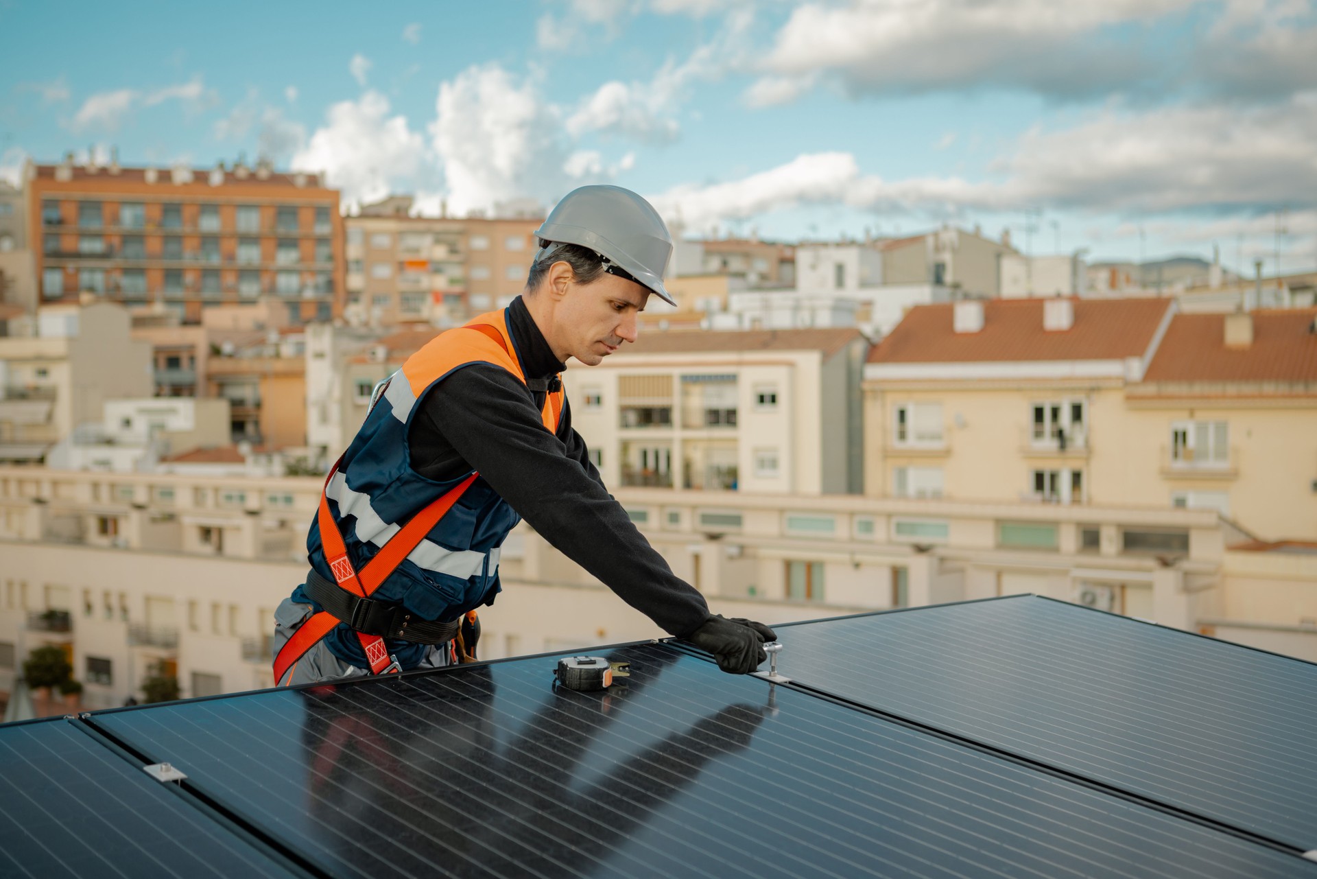 Worker installing solar energy panels on the rooftop of building in the city